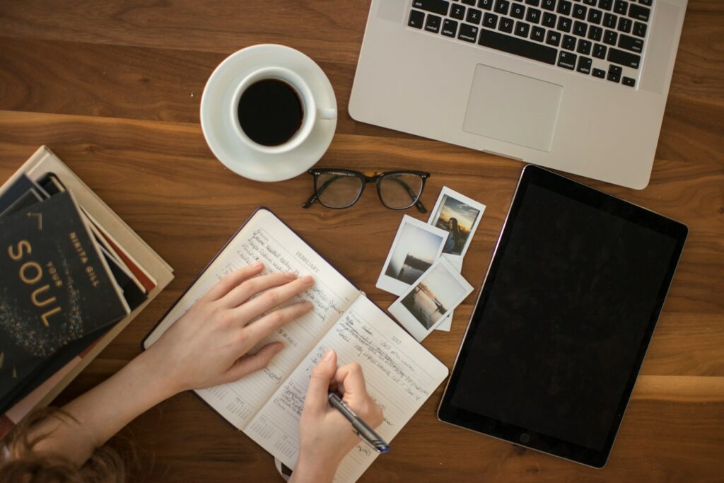 person holding ballpoint pen writing on notebook