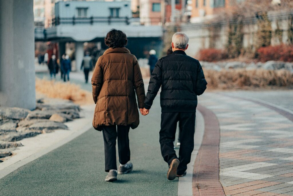 man in brown jacket and gray pants walking on sidewalk during daytime